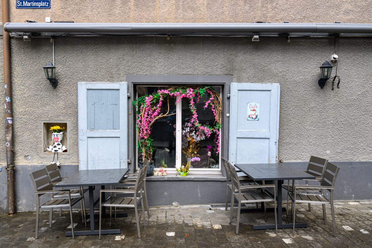 Schöne Café-Fenster mit Blumen und Tischen