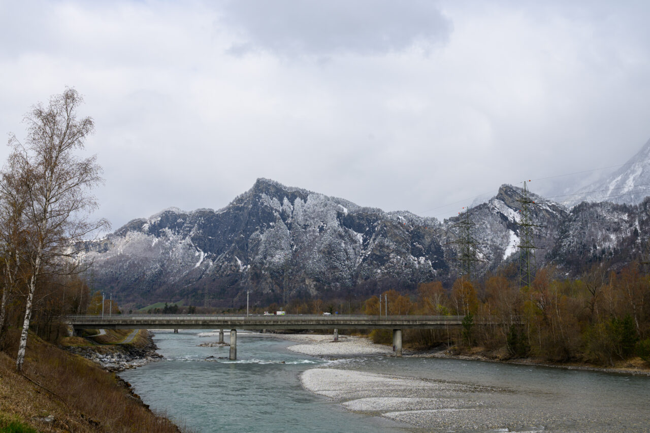 Brücke über einen Fluss mit schneebedeckten Bergen