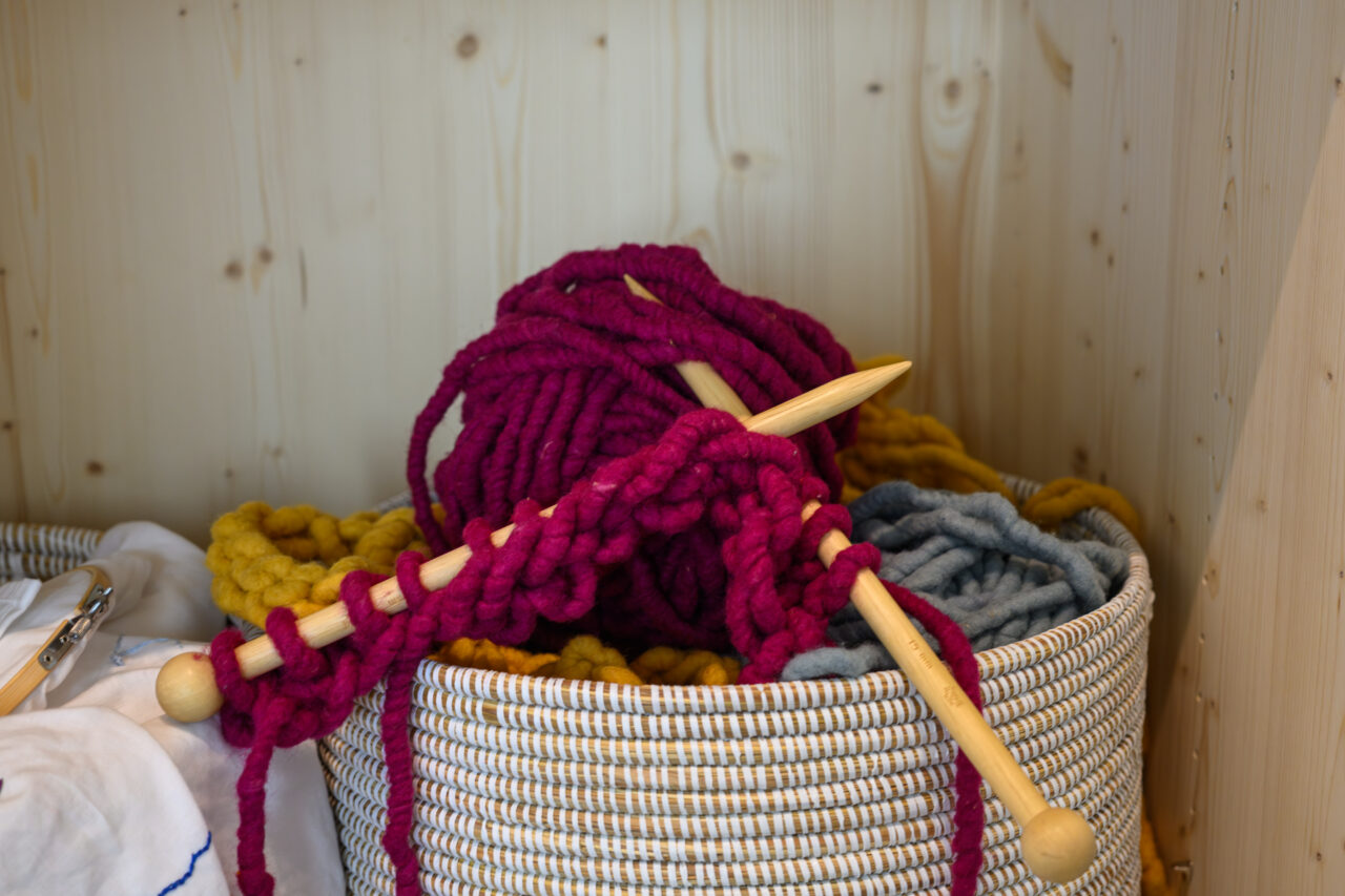 Wolle und Stricknadeln in einem Korb