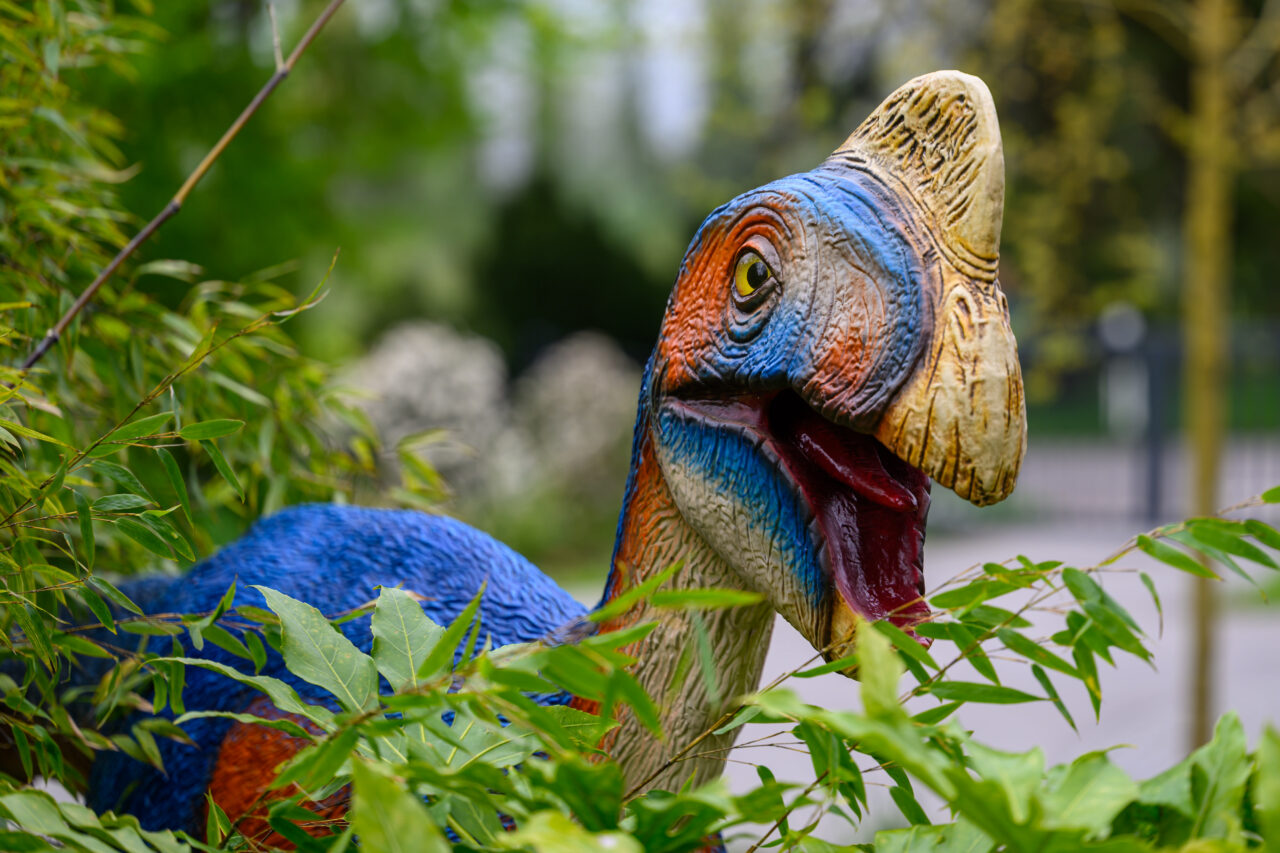 Bunte Dinosaurierfigur im Grünen zwischen Pflanzen